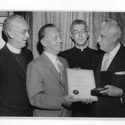 Dr. Bernard P. Widmann showing Shaffrey award medal and certificate to J. Joseph Bluett, S.J., Dr. Tourish, and Mark Bauer, S.J., April 27, 1958.