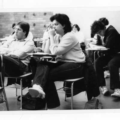 Several students sitting at desks in classroom listening to lecture.