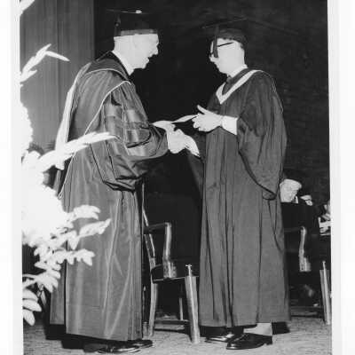 J. Joseph Bluett, S.J., congratulating honnor graduate during 1958 graduation/commencement ceremony.