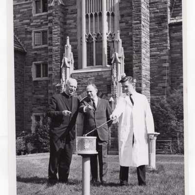 Chemistry professor, Joseph Feighan, demonstrating sensor of Decker nuclear fallout monitor, April 17, 1962, with J. Joseph Bluett, S.J., and another individual watching. Sensor located in front of Lonergan wing of Barbelin Hall.