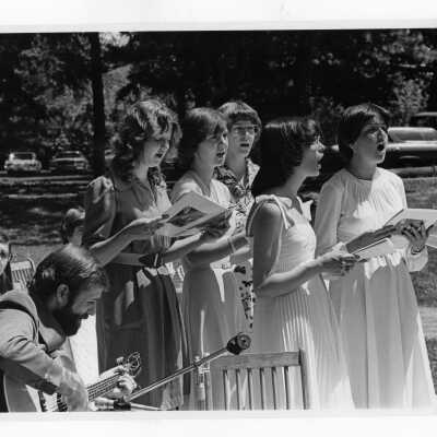 Women's choral group singing outdoors.