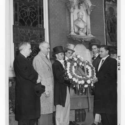 Several students dressed in nineteenth century garb and Edward G. Jacklin, S.J., Joseph Hogan, S.J., and Judge V. Carroll, laying wreath at Father Barbelin's shrine at Old Saint Joseph's Church, Willing's Alley, during centennial anniversary celebration