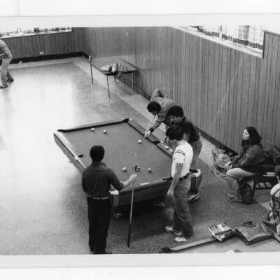 Students playing pool and ping pong in lounge.