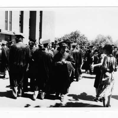 View of graduating students assembling outside Science Center during 1985 graduation/commencement. There is also a photograph of the cover of the commencement program.
