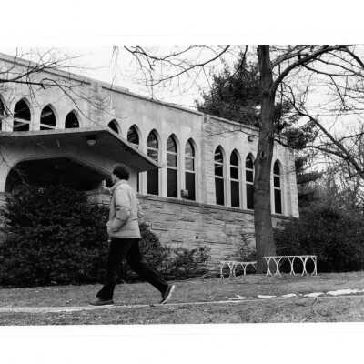 Exterior front of Drexel Library with man walking in front of wall.