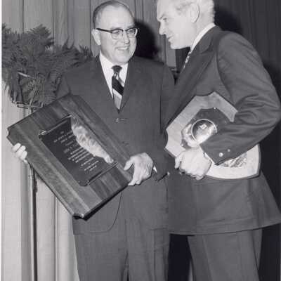 John P. Clark, Jr. holding Hogan Alumni Award plaque with Jack Whitaker congratulating and also hold ing plaque, March 25, 1970.
