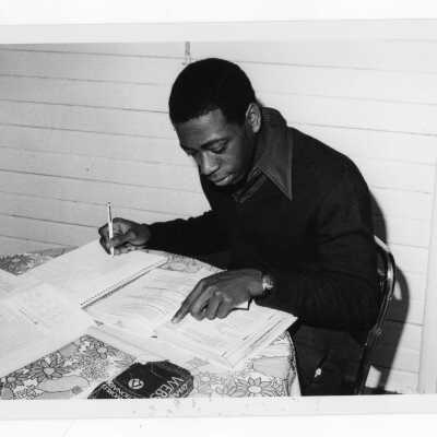 Male student studying at table in dormitory.