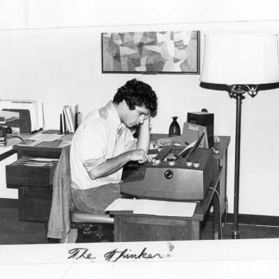 Male student in dormitory room typing paper on electric typewriter.