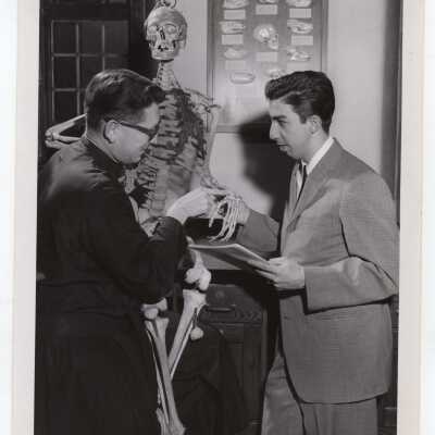 Biology professors Francis J. MacEntee, S.J. with student in science laboratory observing skeleton, February 1963.