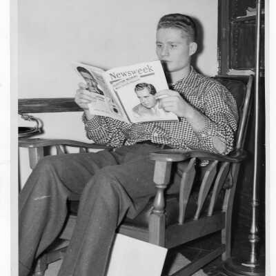 Student resident of Quirk Hall reading Newsweek magazine in living room. Magazine cover has photograph of Richard Nixon.