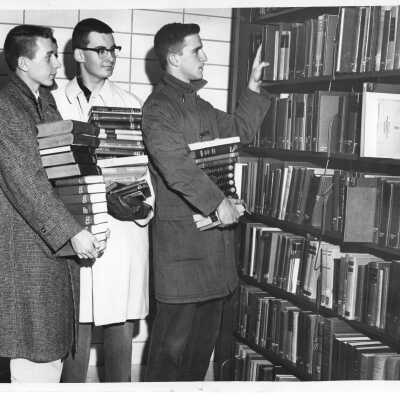 Three students shelving books in new Drexel Library after moving them from Barbelin building.