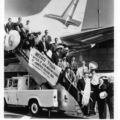 SJC students in Latin American Studies program boarding airplane for Mexico City to participate in internship program, June 1963. Includes Matthew Sullivan, S.J., and others.