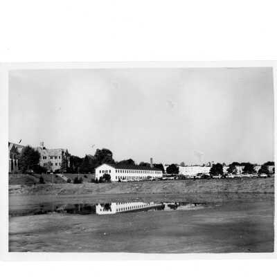 View of Cardboard College (also known as Barbelin Annex) and parking lot with cars from Finnesey Field.