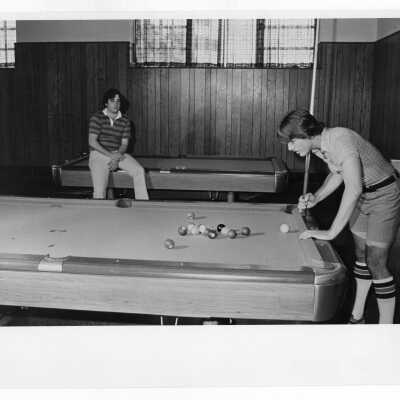 Two students playing pool in lounge.