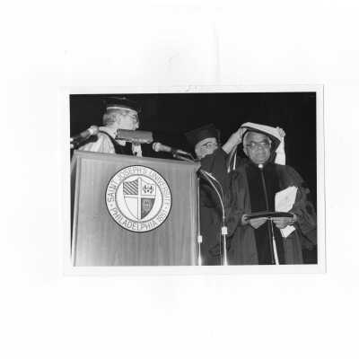 Nicholas S. Rashford, S.J., conferring honorary degree on Cesar Jerez-Garcia, S.J. with William Walsh, S.J. assisting during convocation, March 20, 1990.