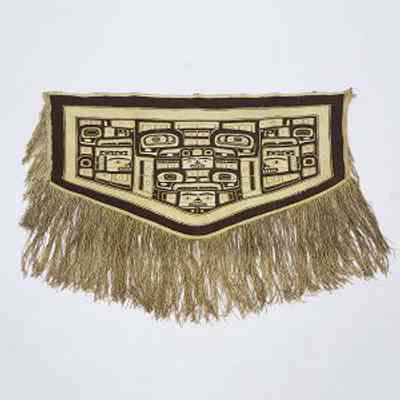 Displayed example of Tlingit Naaxein (Chilkat Blanket), ca. 1880 by unidentified artist showing the basic rectangular shape with the bottom downward point and the dangling fringe on the bottom and sides fundamental to the design and use of the blanket: From Waddington's. See Web Links