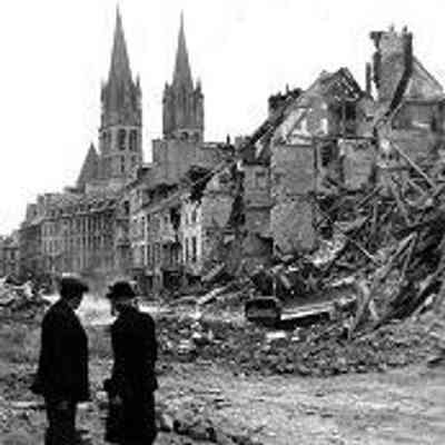 Pair of residents watch Canadian bulldozer clearing away ruins of destroyed houses, rue de Bayeux, Caen. In the background, the two towers of the Abbaye aux Hommes remain intact. July 10, 1944, Photographer unknown: From Library and Archives Canada. Public domain