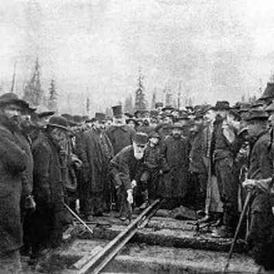 Hon. Donald A. Smith driving the last spike to complete the Canadian Pacific Railway [Craigellachie B.C., Canada]. Reproduction from photograph by Alexander James Ross (1851-1894), Best & Co., Winnipeg, , Nov. 7, 1885. Key figures depicted are CPR director Donald Smith (later Lord Strathcona and Mount Royal) driving the spike, and to Smith's right - the then CPR general manager William Van Horne (dark beard) and the then surveyor and company director Sandford Fleming (white beard): From Library and Archives Canada (Item ID number 3194527)