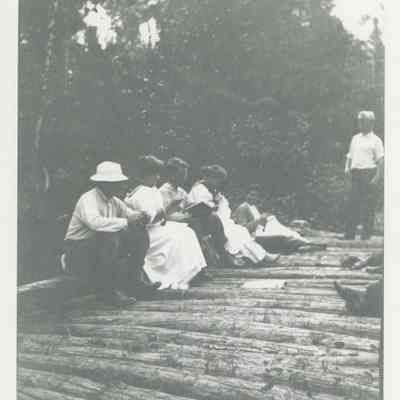 Group of people sitting on a log bridge
