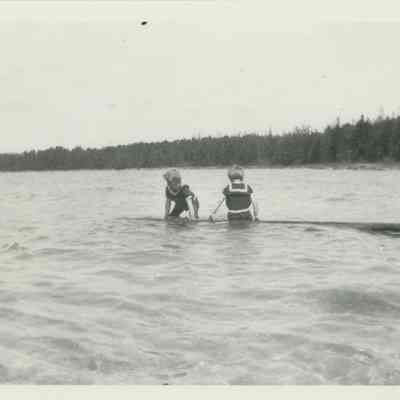 Two children on a log in Lake Huron