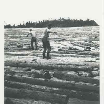 Men balancing on floating logs