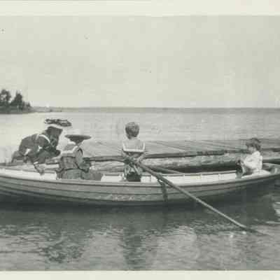 Four people with a rowboat at a dock