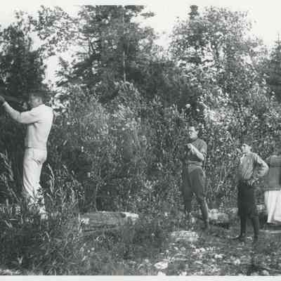 Group watching a man shoot a rifle