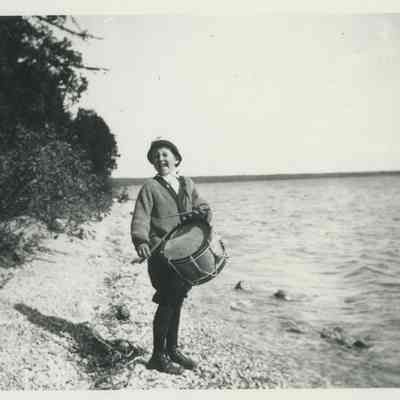Young boy with a drum on the shore of Lake Huron