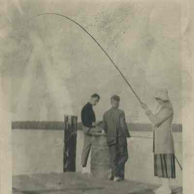 Three people fishing from a dock