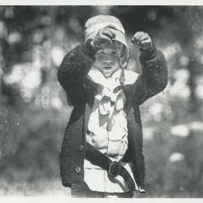 Young child holding a frog by its legs