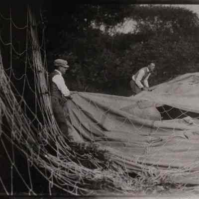 Two men pulling on deflated balloon