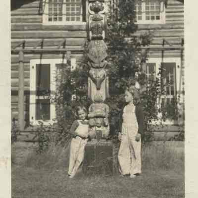 Sally and Gertrude Harrison standing by the totem pole at Cedar Lodge