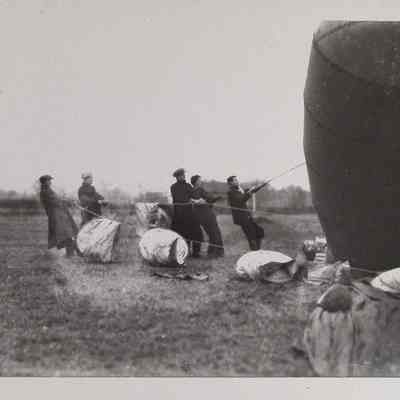 Five men hold cables attached to observation balloon
