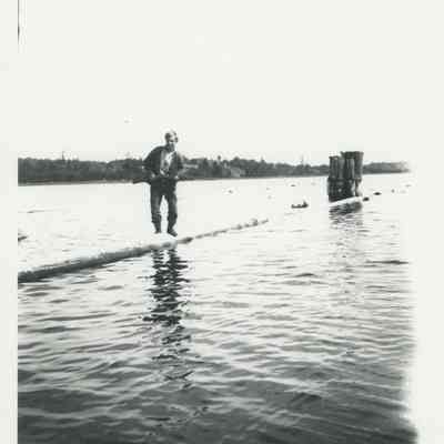 Fred Seiberling balancing on a log with a rifle