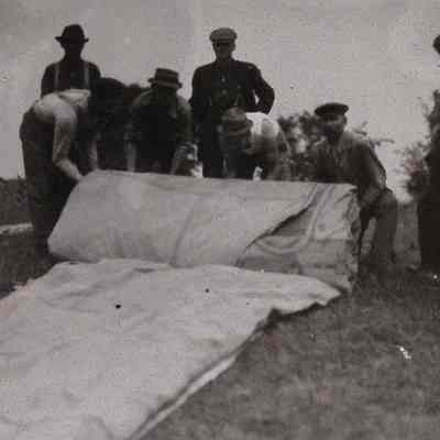 Men rolling a folded, deflated balloon