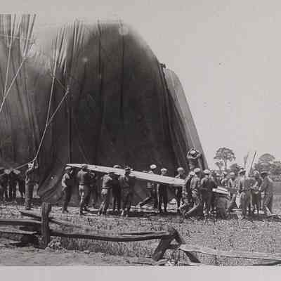 Group of men moving a deflating dirigible