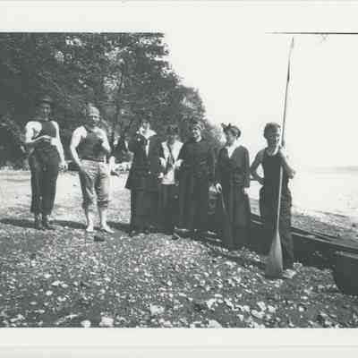Seven people on the shore with canoes