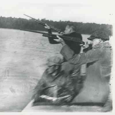 Men shooting rifles from a boat