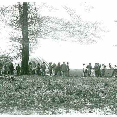 Group of people surround crashed dirigible