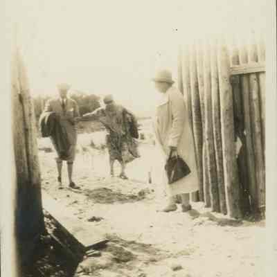 People walking through a stockade fence
