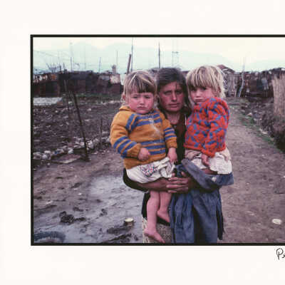 A mother and her daughters on a muddy path leading to a shanty town in Albania's capital city, Tirane