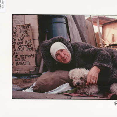 An elderly homeless woman covers her dog with her coat in shantytown near Moscow's Kremlin. Moscow, Russia