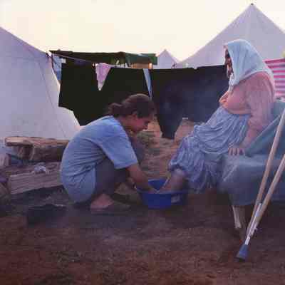 A Kosovar-Albanian young woman washes the feet of her grandmother in a refugee camp during the war in Kosovo, Kukes, Albania