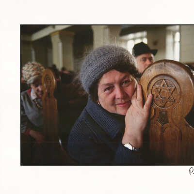 A woman sitting in the pews of a synagogue, touching the Star of David, Moscow
