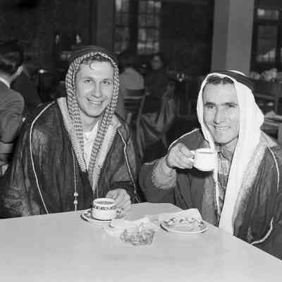 Men in shepherd's outfits drinking tea