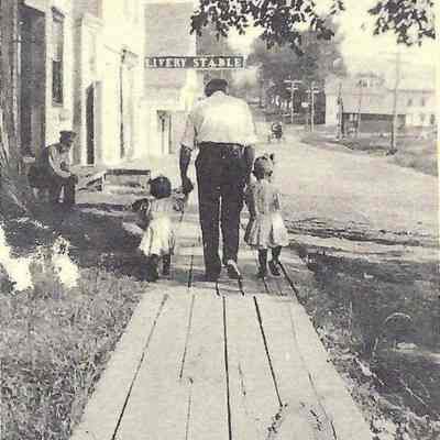 Walking north along the sidewalk: wooden sidewalk, early 1900s