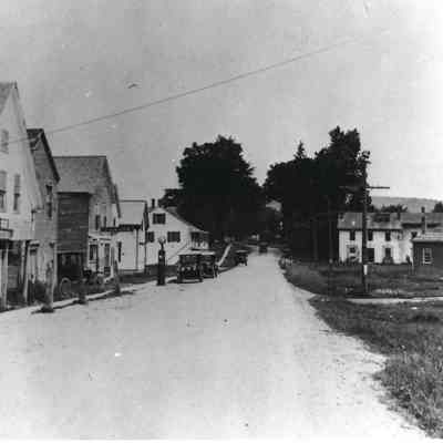 View looking north from middle of road: Gas tanks on left at Rankin's garage, Community Hall on right