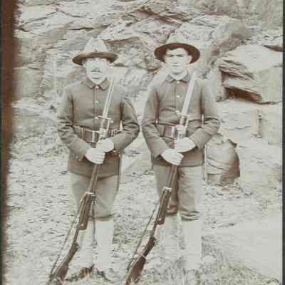 2 men in uniform with rifles standing outside
