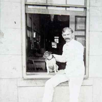 Male leaning on window sill holding dog