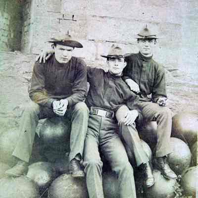 3 men in uniform casual pose on cannon balls